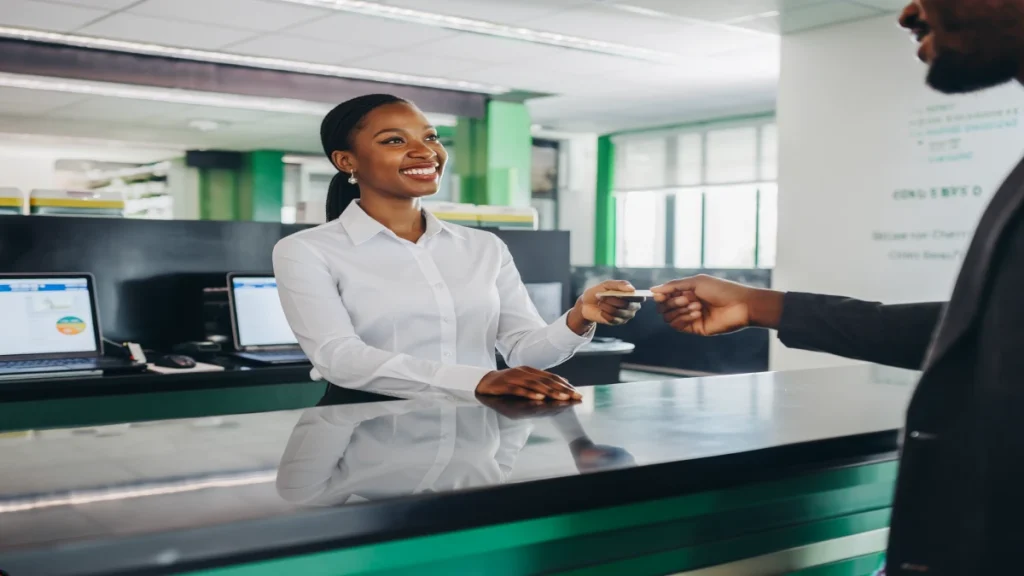 Smiling bank teller assisting a customer in a modern Kigali bank branch.